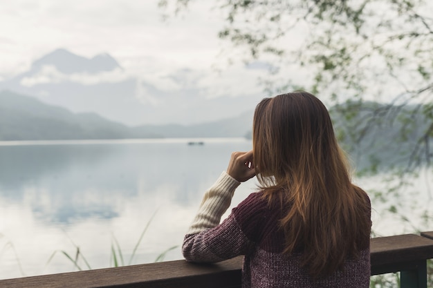 Lonely woman standing absent minded and looking at the river