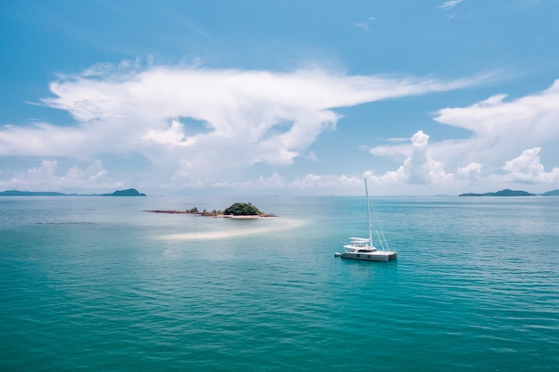 A lonely yacht drifting in the azure warm ocean, heading for a mysterious island in the middle of the ocean. Traveling. Luxury vacation. Warm Ocean. Paradise.