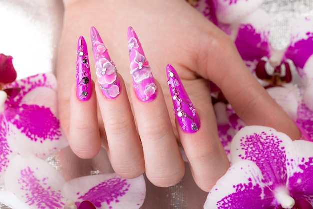 Long beautiful manicure with flowers on female fingers Nails design Closeup Picture taken in the studio on a white background