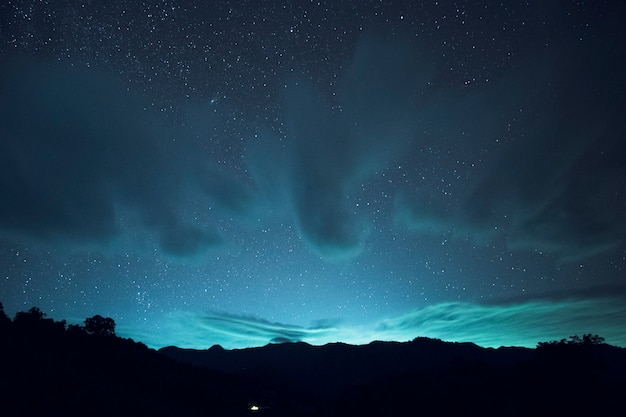 Long exposure and High ISO shot of star and cloud over the mountain at night. blue tone effect. I