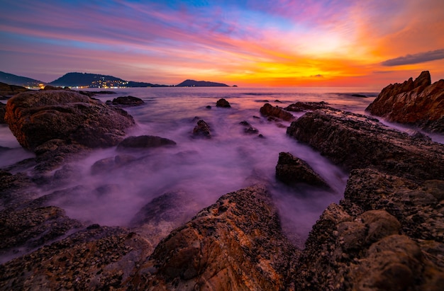 Long exposure image of Dramatic sky seascape with rocks in the foreground sunset or sunrise over sea scenery background.