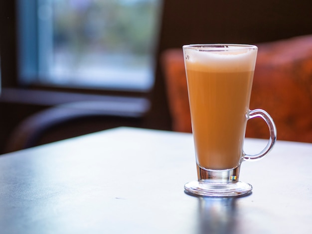 Long glass cup of cappuccino on a wooden table with copy space