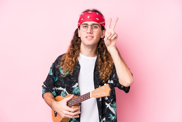 Long hair hippie man holding a ukelele isolated showing victory sign and smiling broadly.