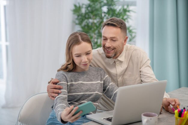 Long-haired girl in grey shirt feeling good with her father