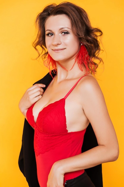 Long handmade red ostrich feather earrings on a brunette girl in a red sexy top Girl posing on orange background