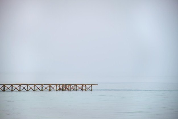 Long horizontal pier bridge on blue sky and water copyspace background