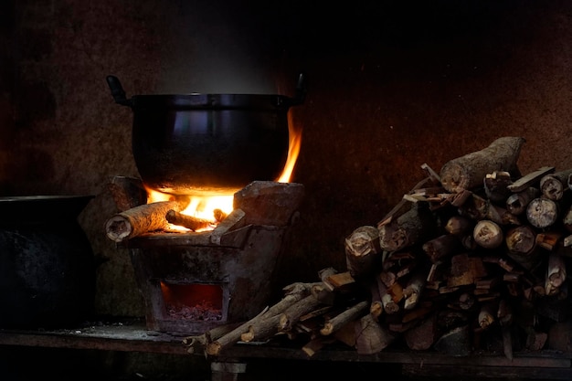 Long orange frame from burning firewood (in a old style stove) is heating to a Pot