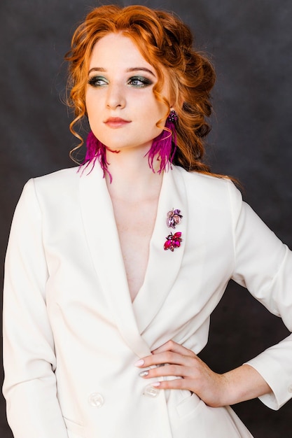 Long purple ostrich feather earrings and beetle brooches on a redhaired girl in a white jacket Girl posing on a black background