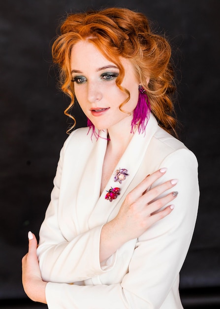 Long purple ostrich feather earrings and beetle brooches on a redhaired girl in a white jacket Girl posing on a black background