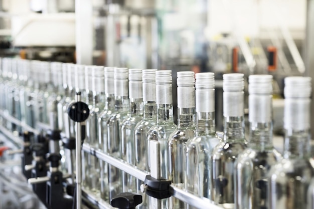 A long row of glass bottles on the conveyor The bottles are closed with a screw cap