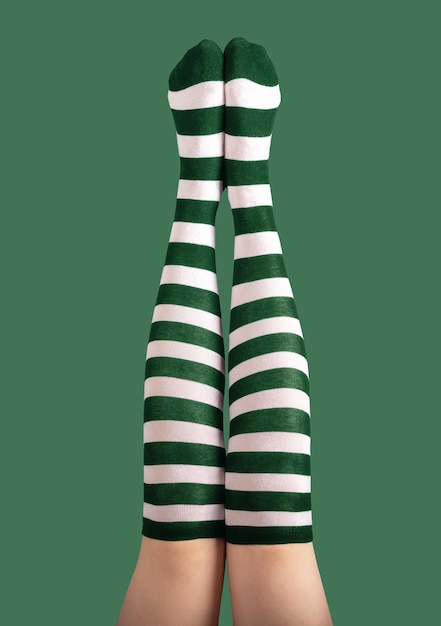 Long sexy female legs stretched high up in striped green and white stockings tights for St Patrick holiday 17 March party