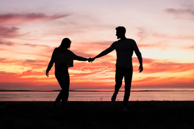 Long shot of couple holding hands at sundown