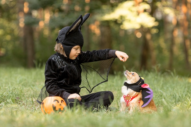 Long shot of little boy in bat costume and dog