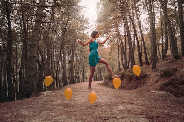 Long shot woman stepping on levitating balloons