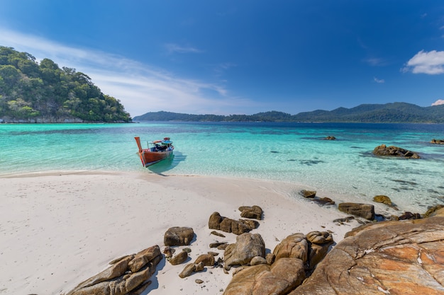 Long tail boat on white sand beach on tropical island in thailand