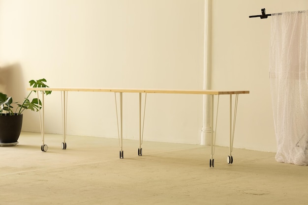 Long wooden minimalistic table on the whees standing in the middle of the light room