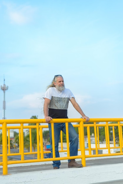 Longhaired grayhaired man on a pedestrian bridge overlooking the city