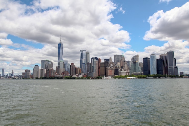 :Look on the sailboat is cruising in New York harbor buildings of Manhattan island in the background.