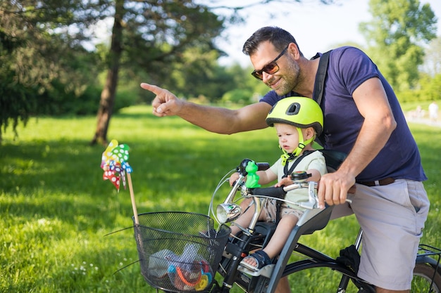 Look over there active family day in nature father and son ride bike through city park on sunny summ