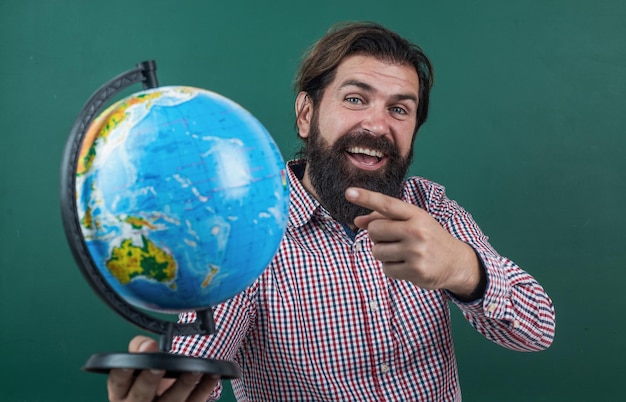 Look over there back to school informal education happy mature teacher pointing at globe bearded man geographer work in classroom with map prepare for exam college lecturer on geography lesson