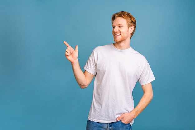 look over there! happy young handsome man in casual pointing away and smiling 