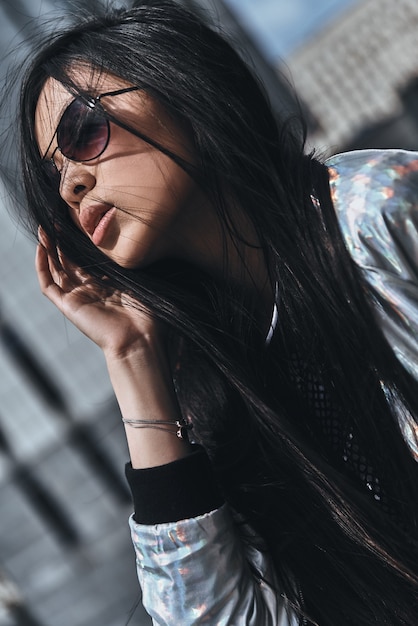 Looking amazing. Beautiful young woman in casual wear keeping hand in hair 