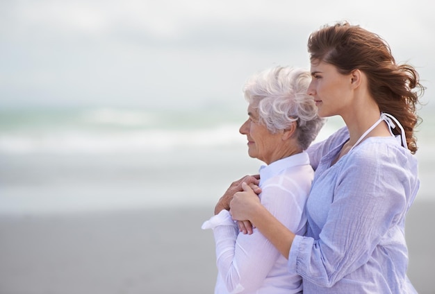 Looking back on their lovefilled years together Shot of a beautiful young woman and her senior mother on the beach