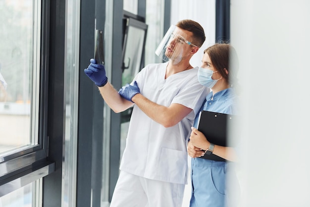 Looking at documents Two doctors in uniform standing indoors and working together