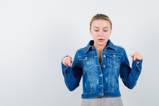 The looking down blonde woman is pointing down with forefingers on white background