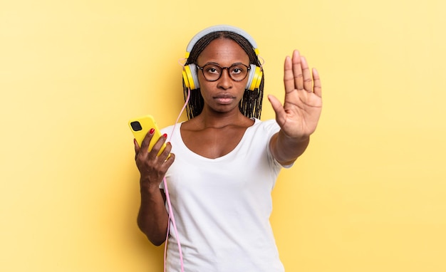 Looking serious, stern, displeased and angry showing open palm making stop gesture and listening music