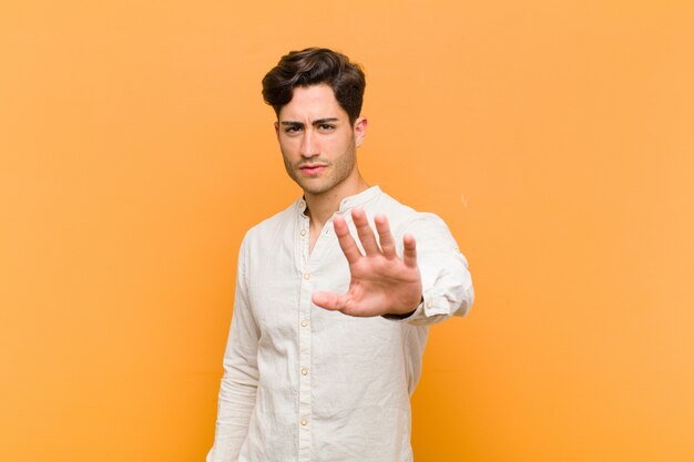 looking serious, stern, displeased and angry showing open palm making stop gesture