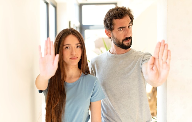 looking serious, stern, displeased and angry showing open palm making stop gesture