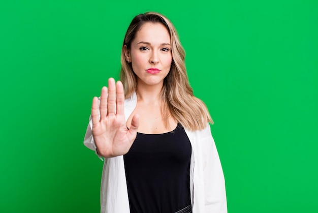 Looking serious stern displeased and angry showing open palm making stop gesture