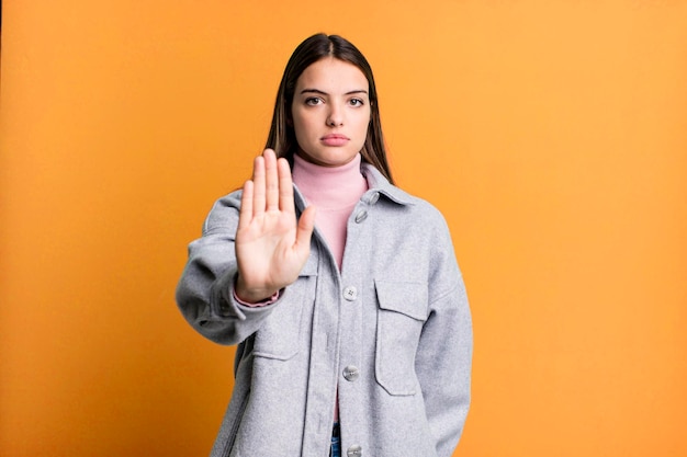 Looking serious stern displeased and angry showing open palm making stop gesture