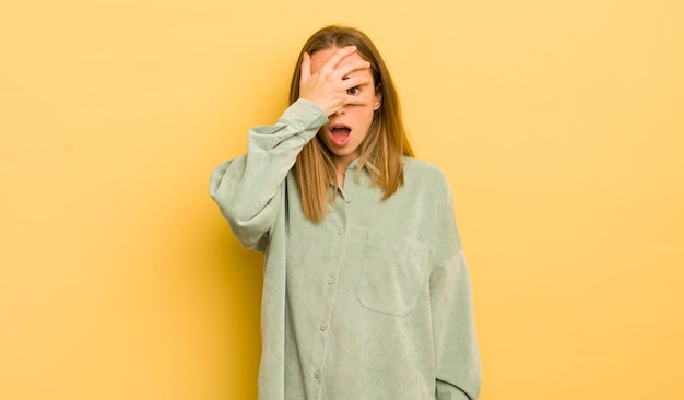 Photo looking shocked scared or terrified covering face with hand and peeking between fingers