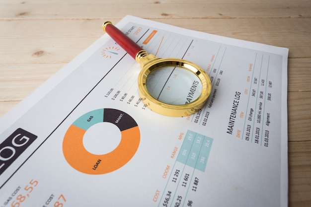 Looking through magnifying glass to financial report