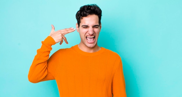 Looking unhappy and stressed suicide gesture making gun sign with hand pointing to head