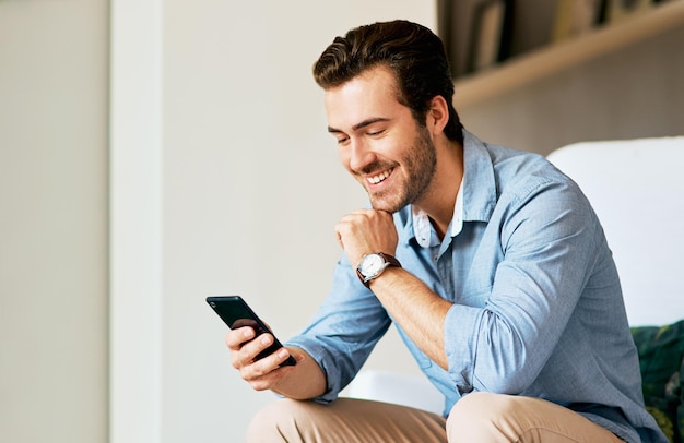 Looks like theres a lot buzzing online Shot of a handsome young man texting on a cellphone at home