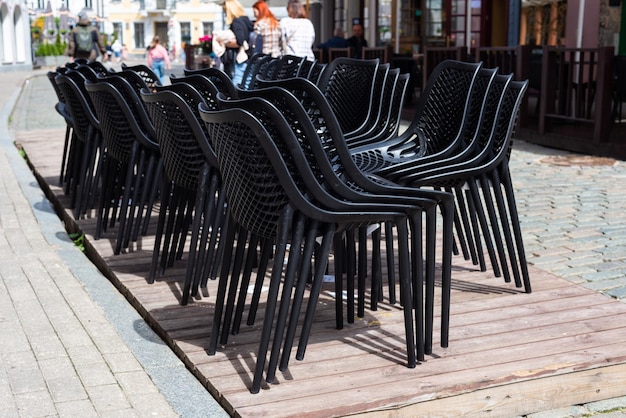 Lot of black plastic chais stacked on the street