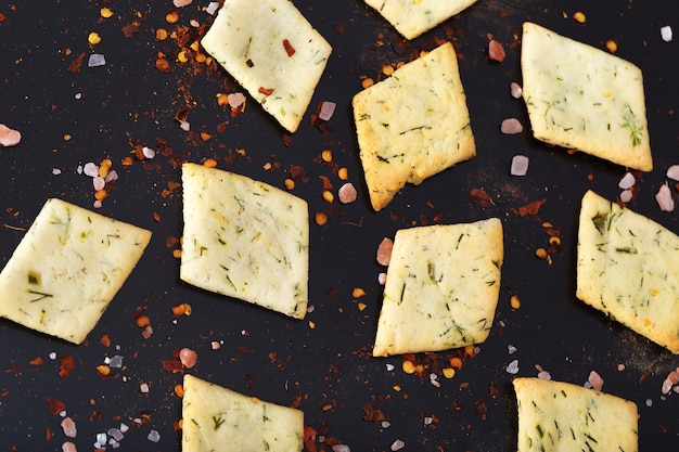 A lot of bread chips are unevenly located on a black table.