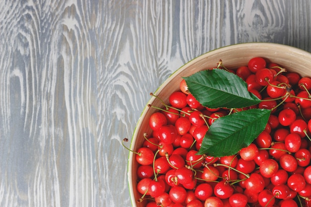 A lot of cherries in a big plate on a wooden table, copy space