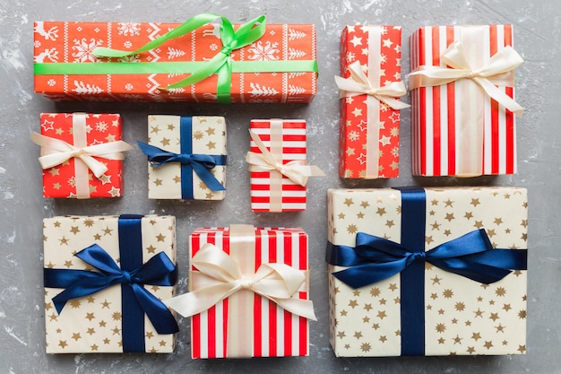 A lot of Christmas gift boxes in colored paper decorated on table Top view close up Many present New Year gift