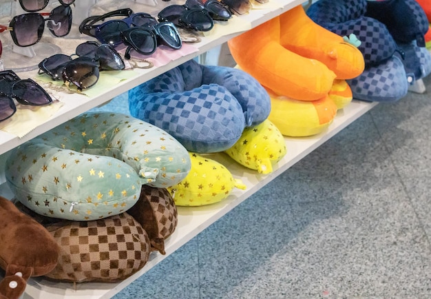 A lot of colorful inflatable and soft pillows for the convenience of the neck during travel lie on the counter of the store the concept of selling goods on the road