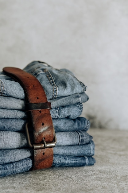 Lot of different blue jeans Blue Jeans, stack of jeans and brown belt.