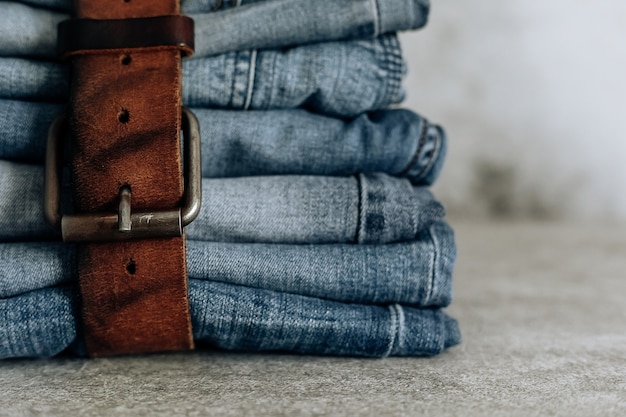 Lot of different blue jeans Blue Jeans, stack of jeans and brown belt.