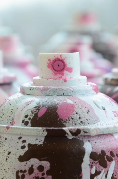 A lot of dirty and used aerosol cans of bright pink paint. Macro photograph with shallow depth of field. 