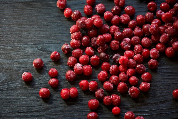 A lot of frozen cherry without sticks on a wooden black background Vitamins and a healthy diet