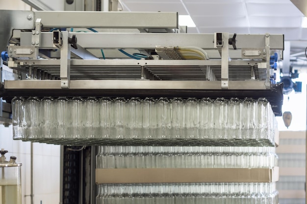 A lot of glass bottles hanging in a pneumatic gripper Unloading glass bottles from pallets