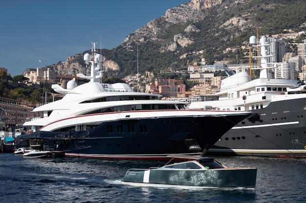 A lot of huge yachts are in port of monaco at sunny day monte carlo mountain is on background glossy...