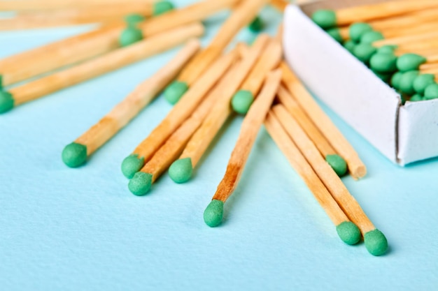 A lot of matches with green heads in a matchbox and near the box on a blue background